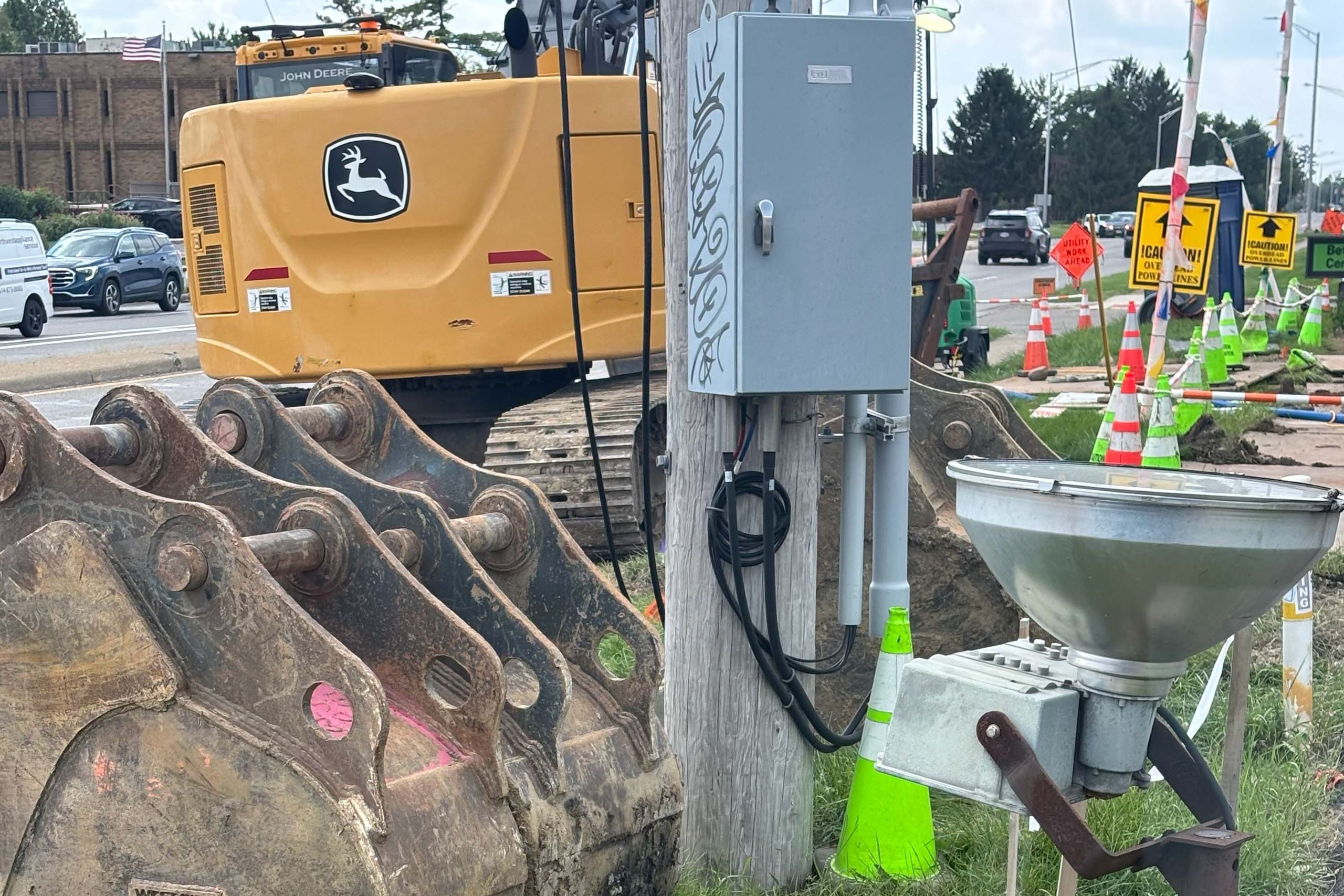 Excavator buckets lined up beside a street utility project