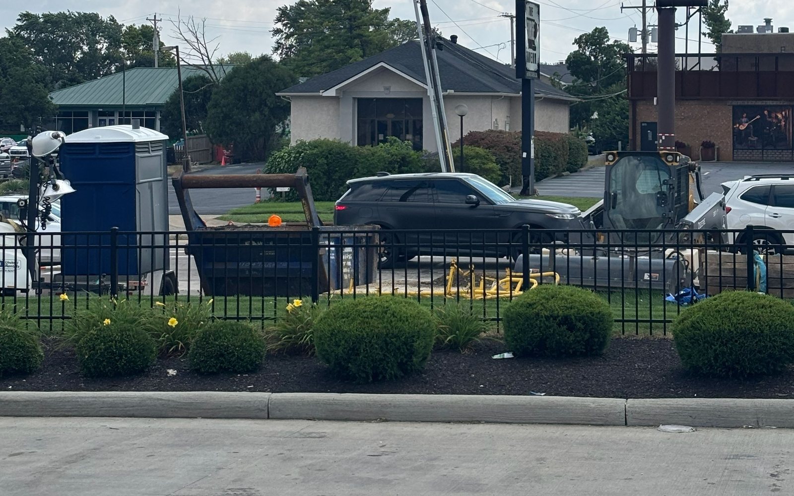 Dumpster, skid steer, and site gear behind the jobsite fence