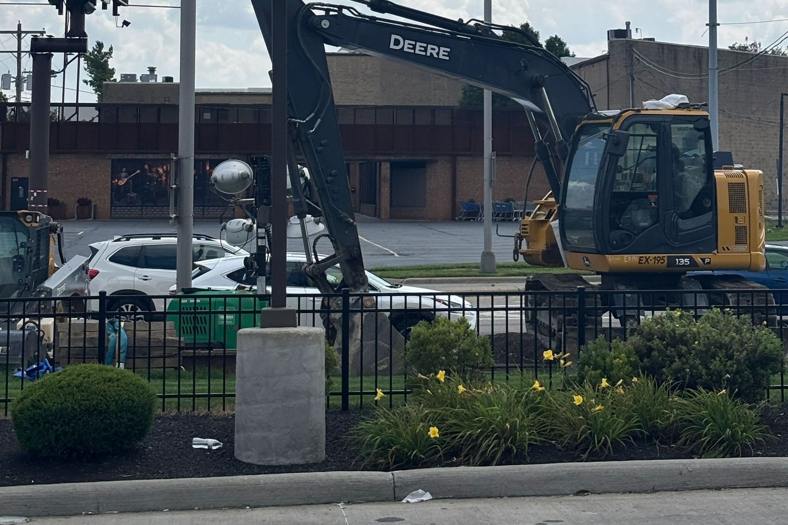 Excavator tracked up beside a row of storefronts