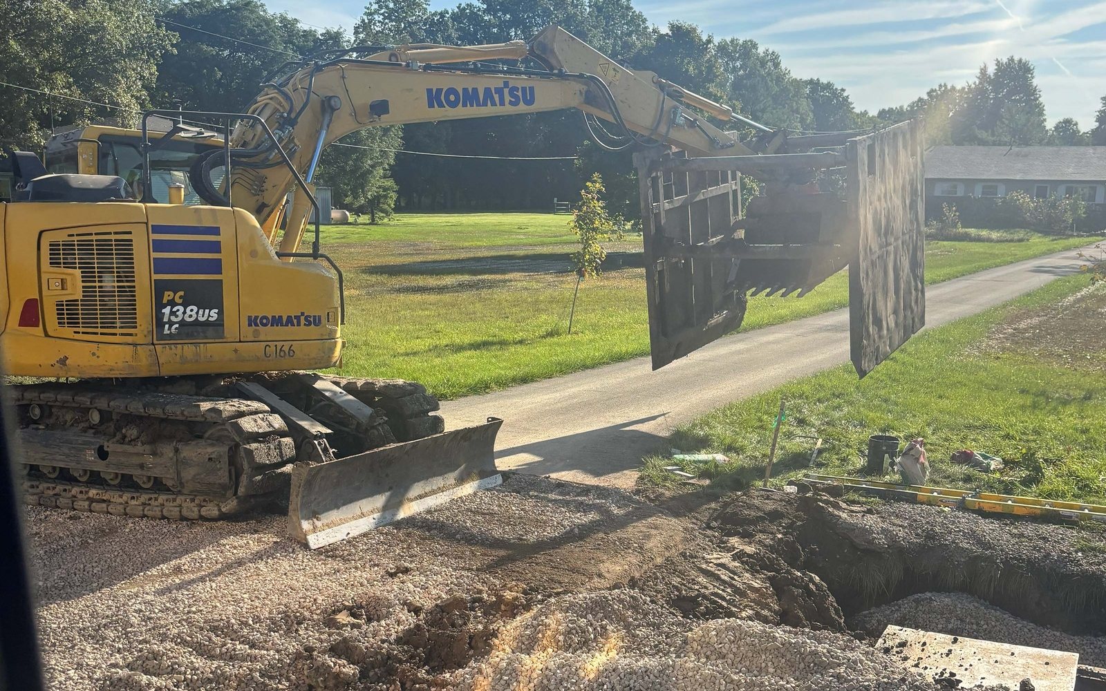 Excavator on a gravel pad beside an open trench