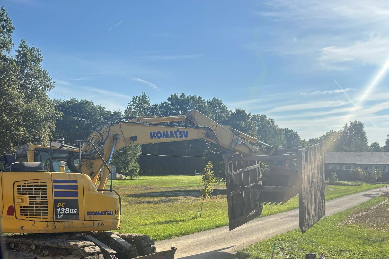 Excavator holding a trench shield steady at a dig site