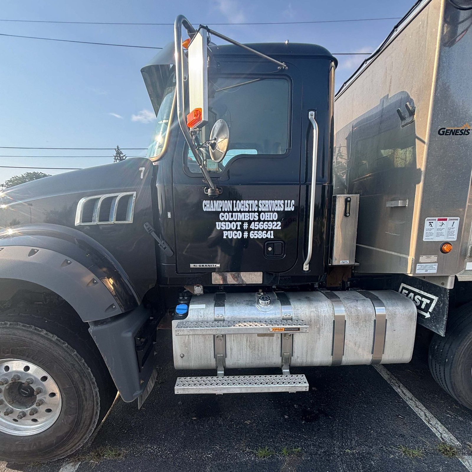 Black Champion dump truck parked with its lettered door in the morning sun