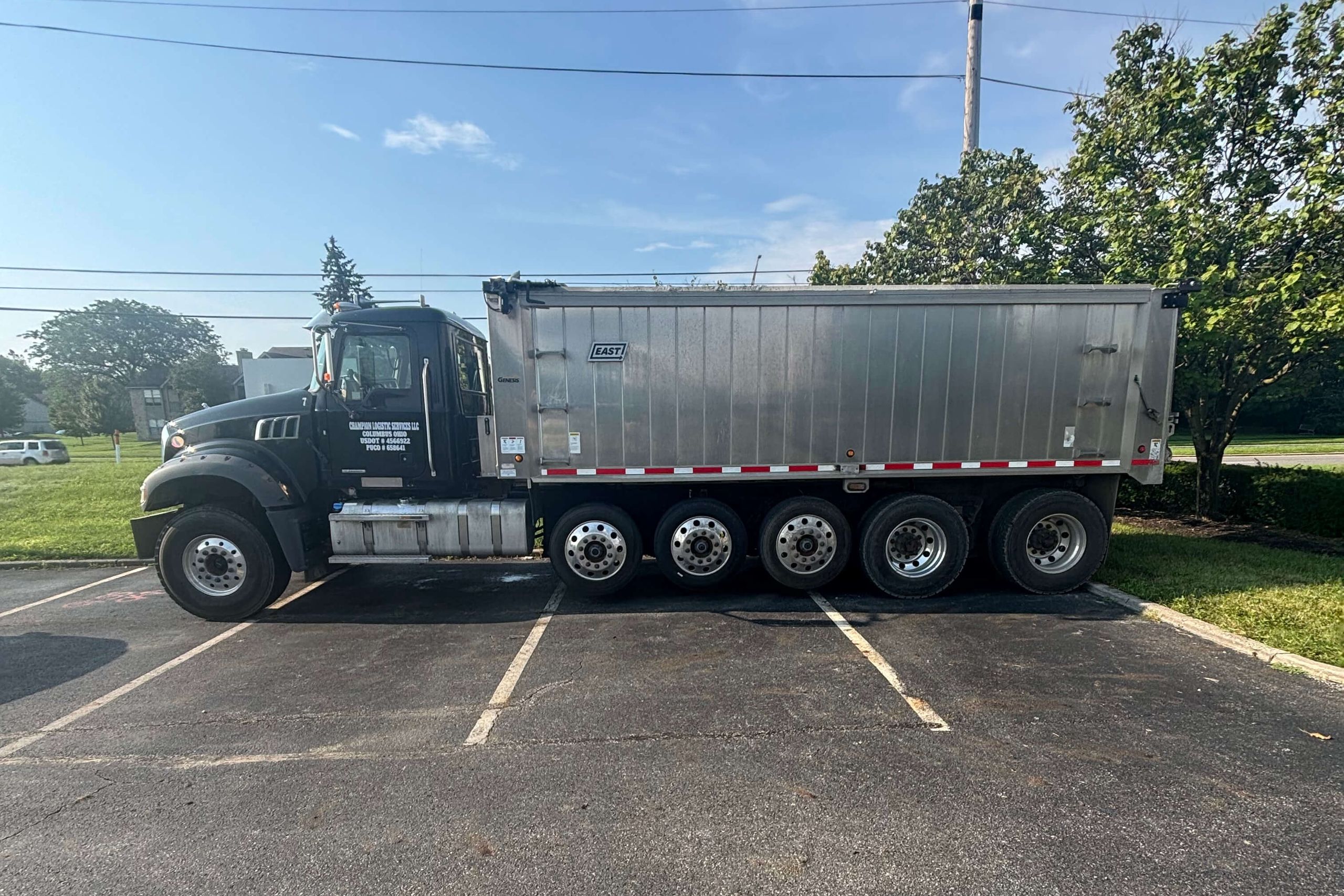 A polished dump truck parked across fresh asphalt