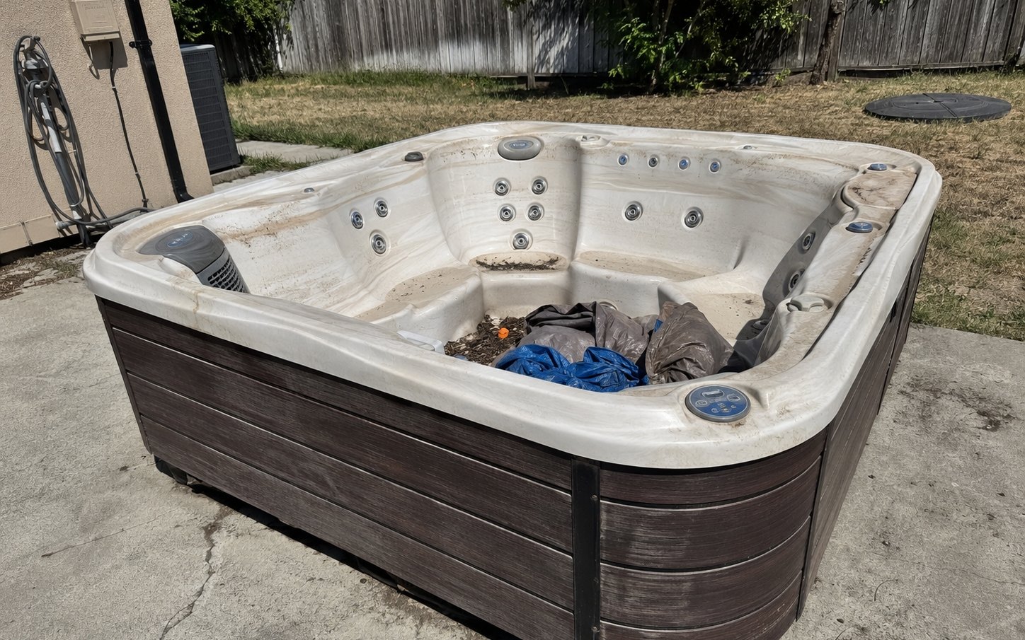An old hot tub sitting on a back patio ready to come out