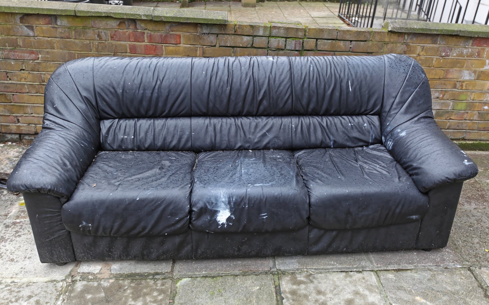 A worn leather sofa set out on the pavement for collection
